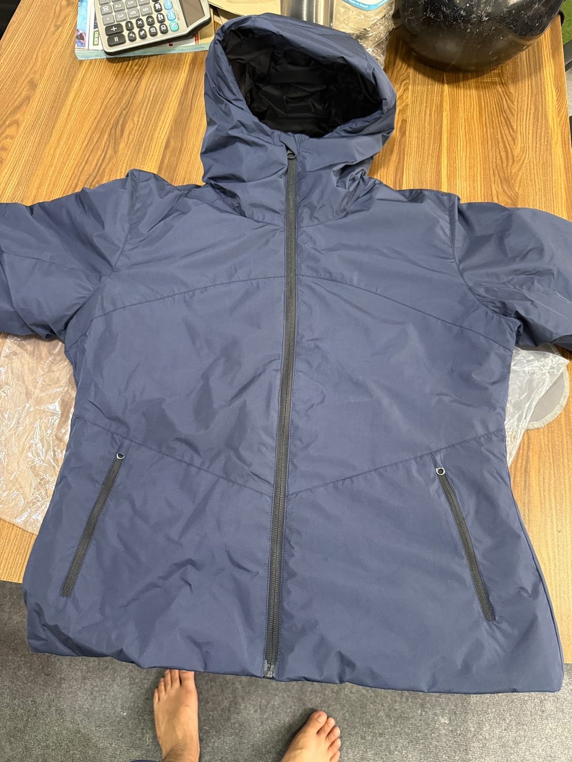 A blue grey hooded jacket laid flat with the hood spread out